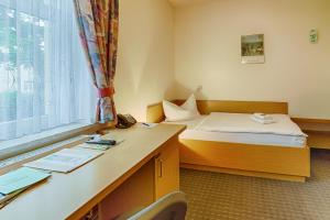a room with a bed and a desk and a window at Hotel am Galgenberg in Gera