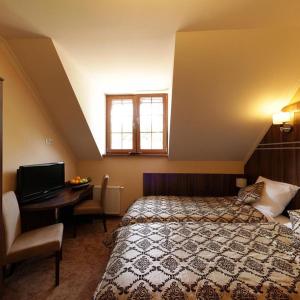 a bedroom with a bed and a desk with a television at Hotel Belfer in Zaniemyśl