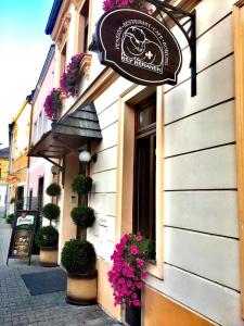 a sign on the side of a building with flowers at Penzion Bily Beranek in Kadaň