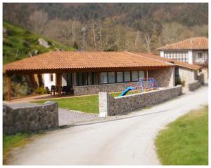 uma casa com um parque infantil em frente em El Molin De Frieras em Posada de Llanes