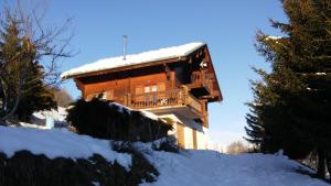 a wooden house with snow on the roof at Spacieux Chalet in Les Chapelles