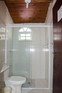 a bathroom with a toilet and a glass shower at Chales Marissol in Ubatuba