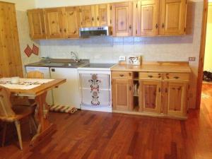una cocina con armarios de madera, mesa y fregadero en Mountain Charming Studio, en Madesimo