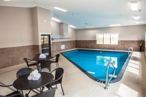 a pool with tables and chairs next to a swimming pool at Heartland Inn Coralville in Coralville