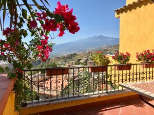 Un balcón con flores y vista a una ciudad. en BellaVista Apartments, en Taormina
