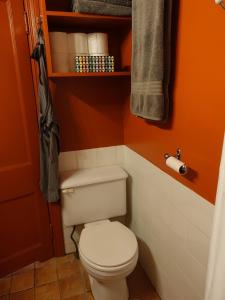 a bathroom with a white toilet in an orange wall at Gite à Coté in Montréal