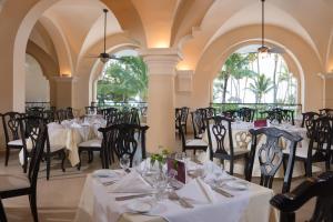 a dining room with white tables and chairs at Occidental Caribe - All Inclusive in Punta Cana