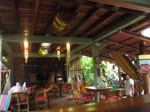 a dining room with tables and chairs and a guitar at Hostal Mamacocha in Montañita