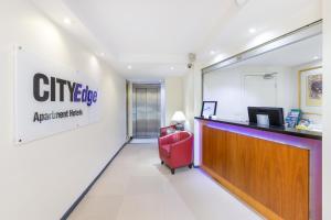 un vestíbulo de una oficina de la ciudad con una silla roja en City Edge East Melbourne Apartment Hotel, en Melbourne