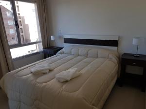 1 dormitorio con 1 cama grande y 2 almohadas en Departamentos Torre 1 en Puerto Madryn