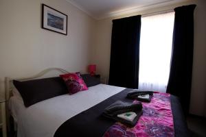 sypialnia z łóżkiem z czarną i różową pościelą i oknem w obiekcie Cape Jervis Holiday Units w mieście Cape Jervis