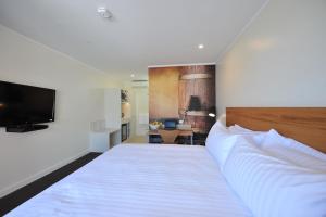 1 dormitorio con 1 cama grande y TV en The Griff Motel, en Griffith