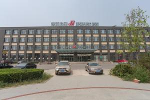 a large building with cars parked in a parking lot at Jinjiang Inn Beijing East Lianshi Road in Beijing