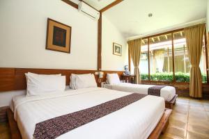 a hotel room with two beds and a window at Cempaka Villa in Borobudur