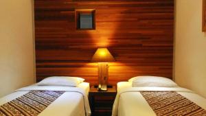 2 Einzelbetten in einem Zimmer mit einer Holzwand in der Unterkunft Rumah Turi Eco Boutique Hotel in Solo + 10 Fotos