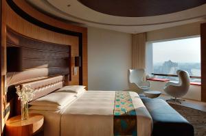 a bedroom with a bed and a chair and a window at Hyatt Regency Chennai in Chennai