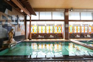 a large swimming pool with a statue in a building at Kamiyamada Hotel in Chikuma