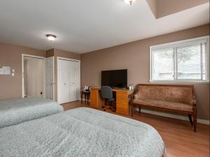 a bedroom with two beds and a desk and a television at Fraser River Richmond Bed and Breakfast in Richmond