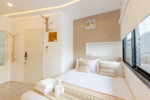 a white room with a bed and a window at The Guest Arak Boutique Hotel in Chiang Mai