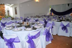 a room with white tables with purple bows at Nooitgedacht Trout Lodge in Lydenburg
