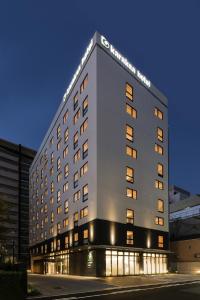 a large white building with lights on it at Karaksa Hotel Osaka Namba in Osaka