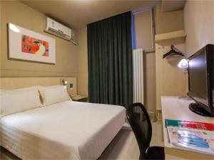 um quarto de hotel com uma cama e uma televisão em Jinjiang Inn Beijing Zhushikou em Pequim