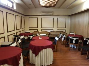 Hotel Polo Towers Shillong في شيلونغ: غرفة طعام مع طاولات وكراسي حمراء