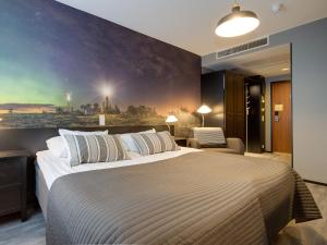 a bedroom with a large bed with a painting on the wall at Original Sokos Hotel Kaarle Kokkola in Kokkola +60 photos