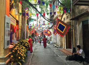 a group of people walking down a street with flags at North Hostel N.2 in Hanoi