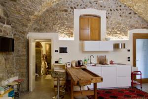 a kitchen with white cabinets and a stone wall at Casa Vacanza Gaia in Costa di Mezzate