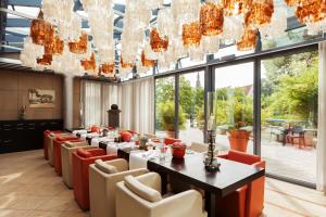 a long dining room with a long table and red chairs at Vienna House by Wyndham Remarque Osnabrück in Osnabrück