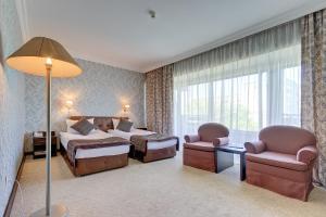 a hotel room with a bed and two chairs at Premier Alatau Hotel in Almaty +27 photos