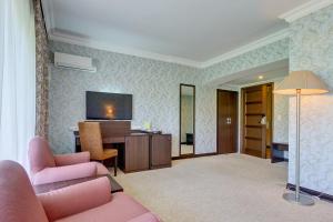 a living room with a couch and a desk and a television at Premier Alatau Hotel in Almaty