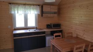 eine Küche mit einem Waschbecken, einem Tisch und einem Fenster in der Unterkunft Gościniec Mazurek , Domek drewniany 1 in Giżycko