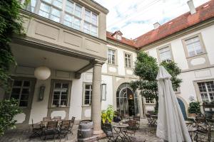 an outdoor patio with a white umbrella and tables and chairs at Palais Schrottenberg in Bamberg