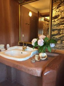 a bathroom sink with a vase of flowers on it at House Smaragdi in Agios Ioannis Pelio