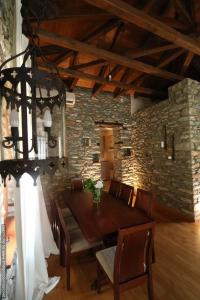 a dining room with a wooden table and a stone wall at House Smaragdi in Agios Ioannis Pelio