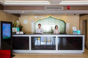 two people standing behind a counter in a lobby at Jinjiang Inn Beijing Hepingmen in Beijing