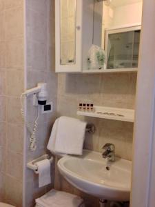 W łazience znajduje się umywalka i lustro. w obiekcie Hotel Dolomiti Des Alpes w mieście Misurina