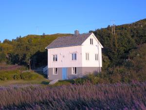 ein weißes Haus an der Seite eines Hügels in der Unterkunft Steinbakk - Vestresand Lofoten in Bøstad