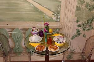 uma mesa de vidro com pratos de comida em 66 Imperial Inn Deluxe B&B em Roma
