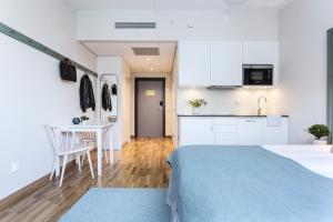 a kitchen with a white refrigerator and a white bed at Biz Apartment Hammarby Sjöstad in Stockholm