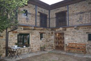 un edificio de piedra con un patio con una mesa y un banco en La Casa de Rosa, en Filiel