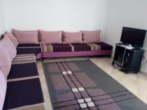 uma sala de estar com um sofá e uma televisão em Appartement Vue Sur Mer Turquoise em Mahdia