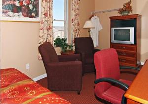 a hotel room with a bed and a tv and chairs at Midtown Inn in Baltimore