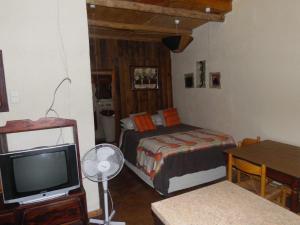 a bedroom with a bed and a tv and a table at Hazyview Country Cottages in Hazyview