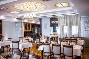 a restaurant with white tables and chairs and a chandelier at Hotel Wodnik in Bydgoszcz