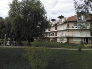 un grande edificio con un albero di fronte di Horváth Apartman a Cserkeszőlő