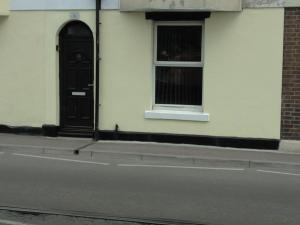 a building with a black door and two windows at Swannery Vista 1 Bedroom Apartment in Weymouth