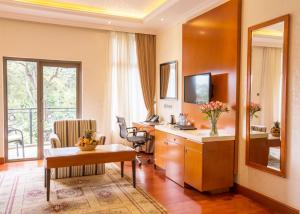 a hotel room with a desk and a room with a window at Alba Hotel Meru in Meru